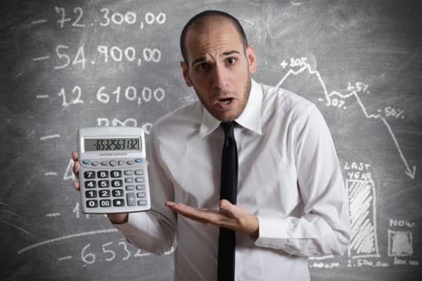 Mann mit Taschenrechner zeigt grosse Minuszahl – Finanzen im Verkaufsgespräch ansprechen