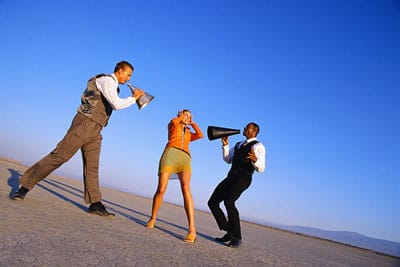 Frau deckt Ohren zu, während zwei Männer mit Lautsprechern Marketingbotschaften brüllen – Marketingberatung und Strategie entwickeln