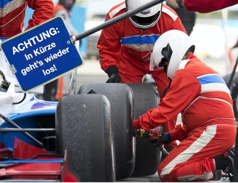 Ein Mechaniker mit Helm wechselt beim Boxenstopp den Reifen eines Rennwagens – Symbol für Neustart, Effizienz und das richtige Timing nach der Krise.