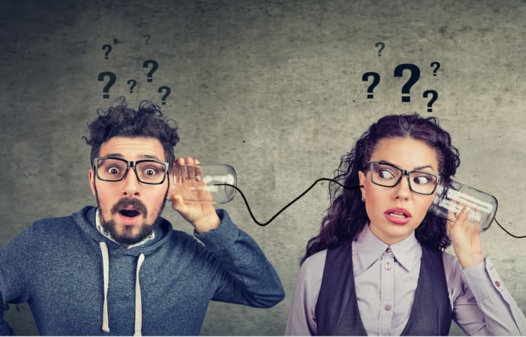 Zwei Personen kommunizieren über ein Schnurtelefon mit Fragezeichen über den Köpfen – Symbol für aktive, wechselseitige Kommunikation im Verkauf und Führung.